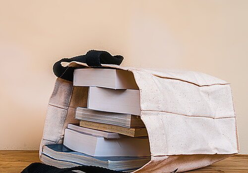 books inside cloth bag on wood table