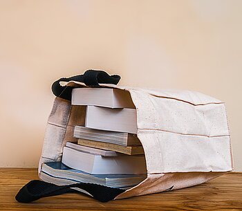 books inside cloth bag on wood table