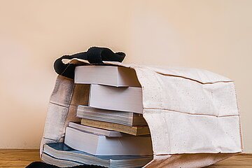 books inside cloth bag on wood table